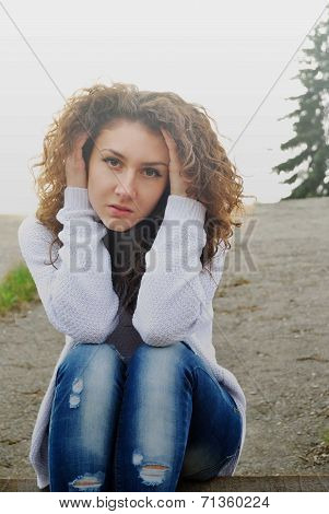 Beauty girl looking to camera sitting on asphalt