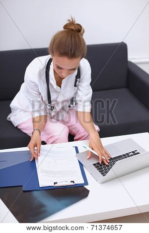 A female doctor filling in casebook at desk isolated on white
