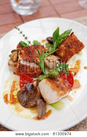 Coalfish fillet with mushrooms and asparagus on plate