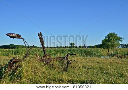 Old vintage plow in long grass