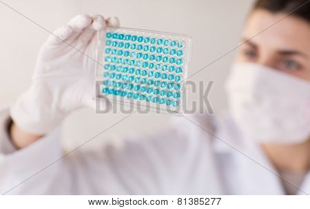science, chemistry, biology, medicine and people concept - close up of young female scientist with pipette and flask making test or research in clinical laboratory