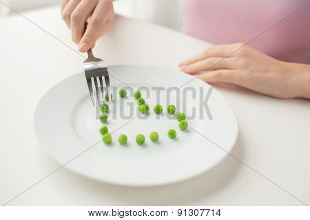 healthy eating, dieting, vegetarian food and people concept - close up of woman with fork eating peas in shape of heart