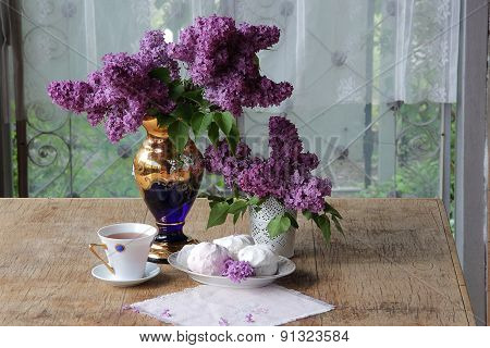 Tea In A Porcelain Cup, A Zephyr And A Lilac Bouquet In A Beautiful Vase