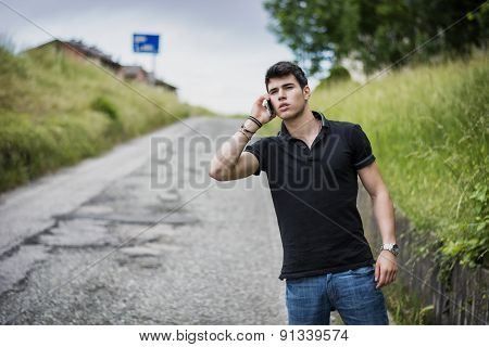 Young Man On Side Of A Road, Calling And Waiting For Taxi