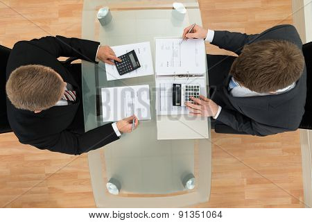 Two Businessman Calculating Bills Using Calculator