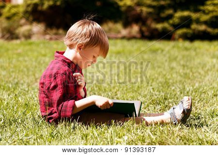 Profile of little boy reading book