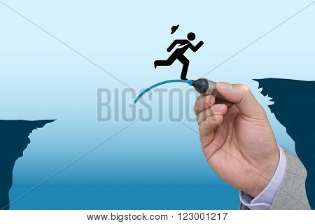 Business hand draws a jump pad to help another business man bridge the gap between two cliffs