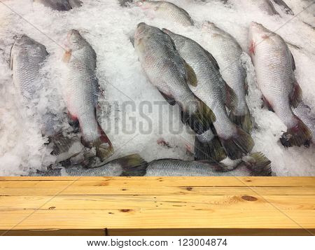 Wood table layout for your products and Many fish freezing on the background.