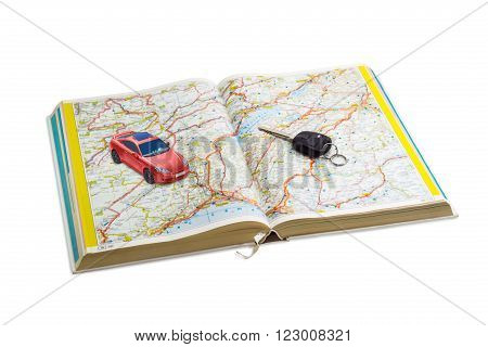 Car key and red toy car on the open road atlas on a light background