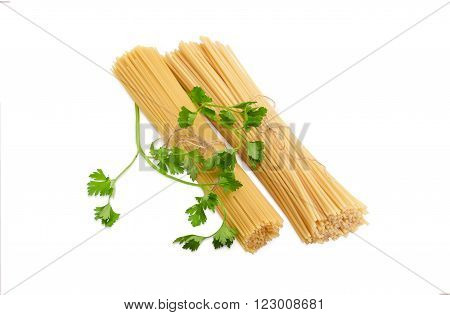Two bundles of different uncooked dried long pasta and sprigs of parsley on a light background
