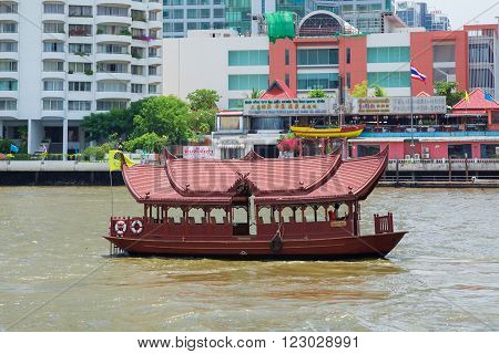 Bangkok, Thailand - Aug 15, 2015: wooden ferry transfer boat with Thai-style roofs and ornate grill work panels crossing the Chao Praya River