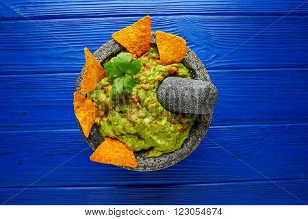 Guacamole with nachos avocado in Mexican molcajete on blue wood table