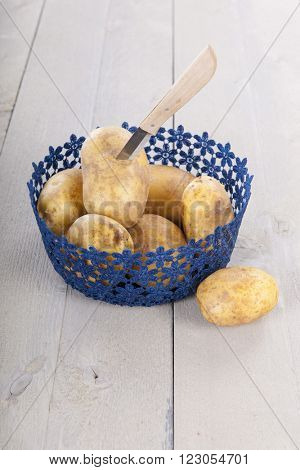 Basket raw potatoes and knife to peel them