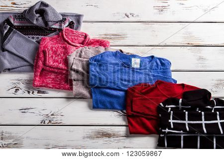 Pullovers of cotton and wool. Different pullovers on wooden background. Stylish warm female clothing. Woman's casual pullovers set.