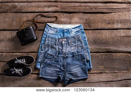 Lady's different length denim shorts. Different shorts on old table. Classic female shorts with keds. Black shoes and vintage shorts.