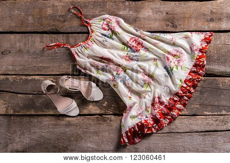 Sarafan with beige heel shoes. Sarafan on aged brown floor. Retro summer clothing sale. Women wore this years ago.