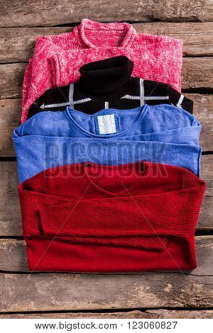 Woman's pullovers of different color. Pullovers on aged wooden floor. Vintage store showcase with pullovers. Stylish sweaters at retro shop.