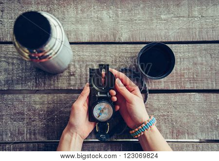 Traveler woman holding compass on wooden table point of view