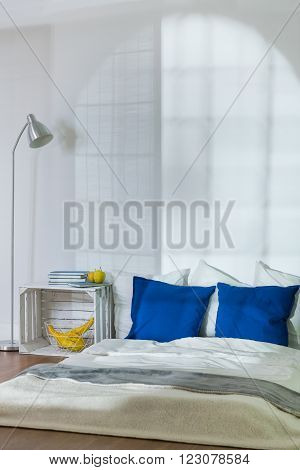 Stylish cozy sleeping place with comfortable mattress on floor in modest bedroom