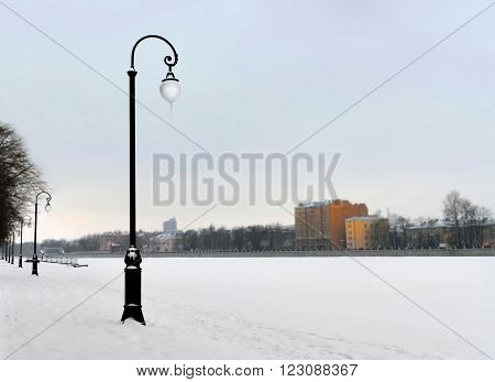 Embankment in the winter. The river which is held down by ice is brought by snow. Fog. Due to the changeable weather icicles on the plafond lamps.