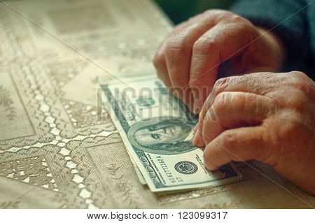 Senior retired woman with small amount of money on table, toned image, colorized, selective focus, very shallow dof.