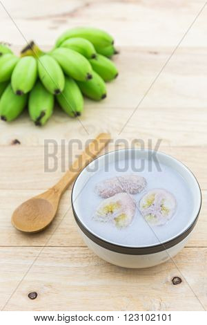Banana in coconut milk (Kluay Buad Chee) on wood desk Thai desert.