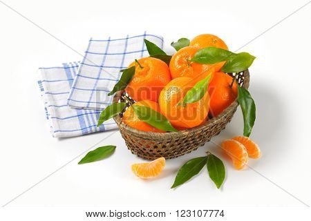 scuttle of ripe tangerines and checkered dishtowel on white background