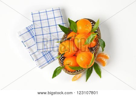 scuttle of ripe tangerines and checkered dishtowel on white background