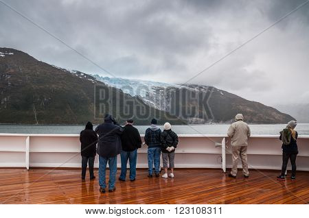 Glacier Alley, Beagle Channel, Chile - December 10, 2012: Passengers on board the cruise ship Veendam viewing beautiful Romanche Glacier on Glacier Alley. Taken on a overcast rainy day. Glacier alley is also of historical importance as it was described in