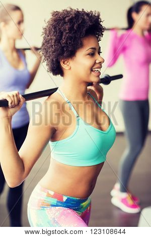 fitness, sport, training, gym and lifestyle concept - group of people exercising with bars in gym