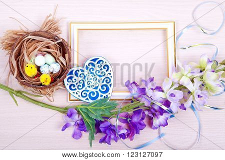 Decorative frame and Easter eggs in the nest on wooden background