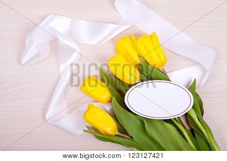 Yellow tulips and plate for an inscription on a wooden background