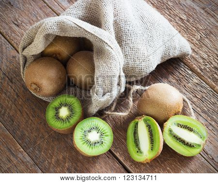 Fresh Juicy Kiwi fruit in bag on brown wooden background