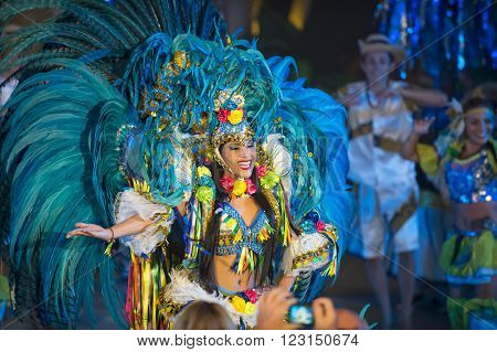 Parintis, Brazil, December 06, 2015: One attractive smiling  tallanted dancer woman in bikini and carnival feather costume bright blue colors and painted face in mask, horizontal photo