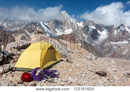 Small Yellow Tent Climbing Gear Rope Ice Axe Red Helmet Rocky Wild Terrain Majestic Peak Range View Blue Sky Clouds