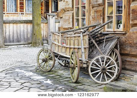 ZAKOPANE POLAND - MARCH 09 2016 Wooden waggon set against the wall of the building constructed in the traditional way with wooden logs. This scene reminds tradition of the region