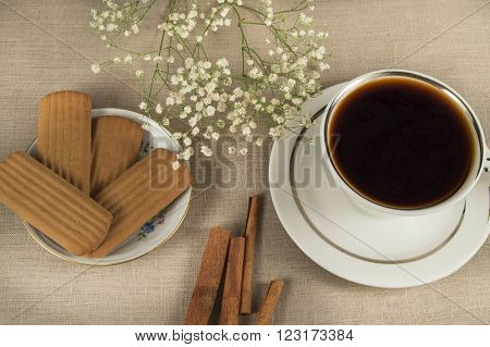 A hot Cup of coffee cinammon cookies on linen napkin.
