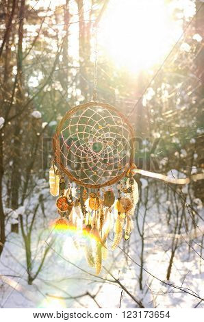 Handmade colorfull dream catcher in the snowy forest. Tribal elements owl feathers
