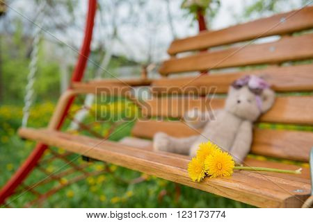 Swing bench near children house in garden with trees and grass