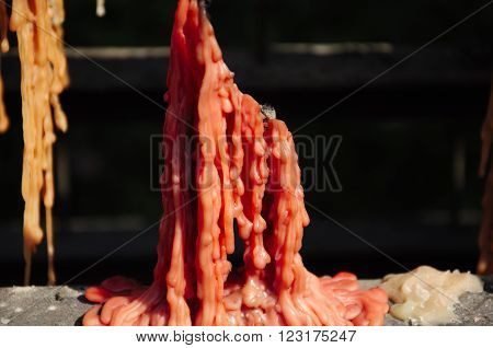 Buddhist prayer candles melted down to create an abstract image of melting red wax.