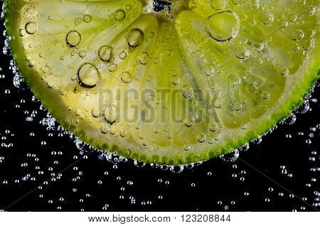 Lemon in a glass with carbonated water bubbles