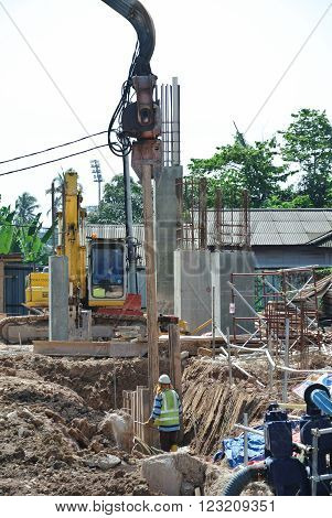 SELANGOR, MALAYSIA - MARCH 12, 2015: Sheet pile cofferdam driven machine at the construction site. This machine drove the sheet pile to the earth using vibrated hydraulic arm. Workers control.