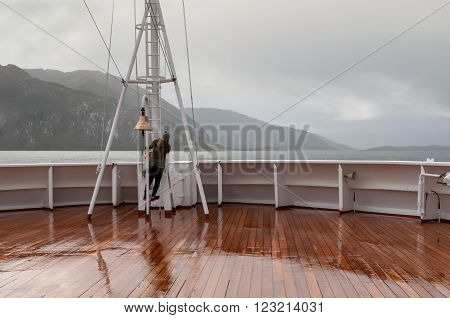 Beagle Channel, Chile - December 10, 2012: Passenger on board the cruise ship Veendam looking forward on the bow on Beagle Channel, Chile. Taken on a overcast rainy day. Sailing down the Beagle Channel in glacier alley and passing in front of these 5 glac