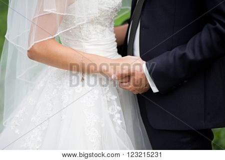 Close up shot of groom and bride holding hands and hugging