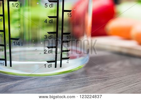 100ml / 1dl Of Water In A Measuring Cup On A Kitchen Counter With Vegetables