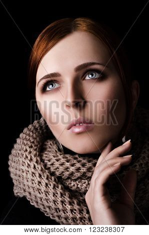 Portrait of a young girl in a scarf-snood large knitting on a black background