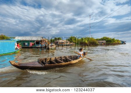 SIEM REAP, CAMBODIA DEC. 16: Cambodian people live on Tonle Sap Lake in Siem Reap, Cambodia on December 16, 2011. Children swim to school by boat.