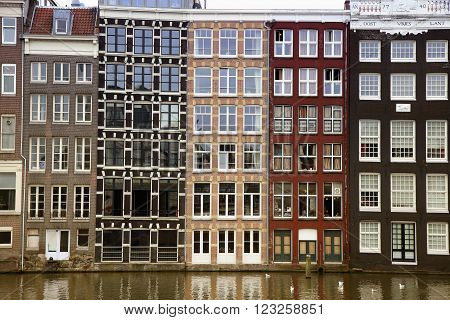 AMSTERDAM; THE NETHERLANDS - AUGUST 16; 2015: Beautiful views of the ancient buildings at the waterside, Damrak canal in Amsterdam. Amsterdam is capital of the Netherlands on August 16; 2015.