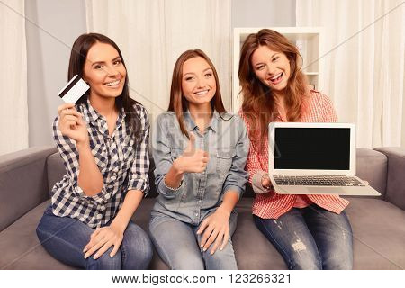 Cheerful Girls Showing Laptop, Bank Card And Gesturing
