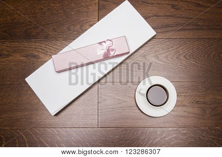 Topview of wooden desktop with girly present case and coffee cup